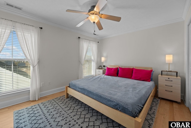 bedroom featuring visible vents, ornamental molding, wood finished floors, baseboards, and ceiling fan
