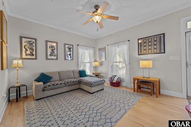 living room featuring crown molding, baseboards, ceiling fan, and wood finished floors
