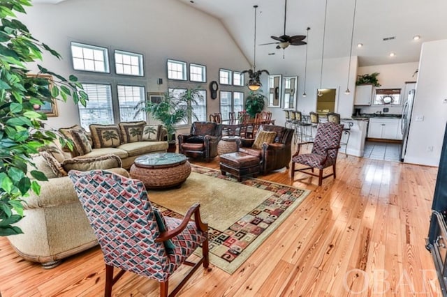 living room with high vaulted ceiling, light wood finished floors, and plenty of natural light