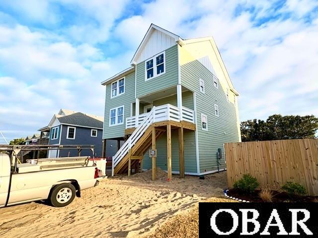 view of front facade with stairs, board and batten siding, and fence