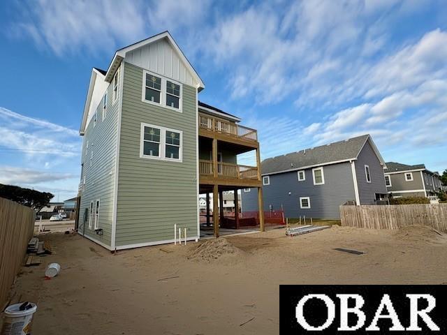 back of house featuring a balcony, fence, and board and batten siding