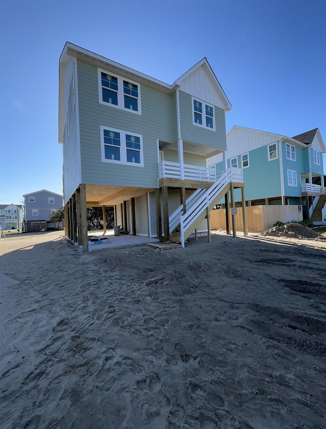 rear view of property featuring a carport, a residential view, driveway, and board and batten siding