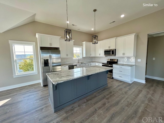 kitchen with stainless steel appliances, a center island, white cabinets, and a sink