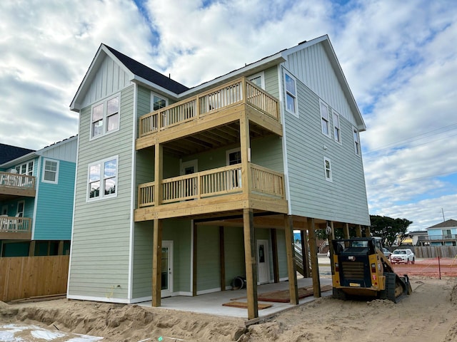 rear view of house featuring a balcony, a carport, a patio area, and board and batten siding