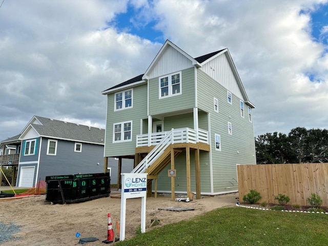 view of front of property with stairs, board and batten siding, and fence