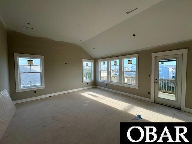 spare room featuring vaulted ceiling and baseboards