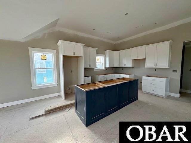 kitchen with white cabinets, a kitchen island, and baseboards