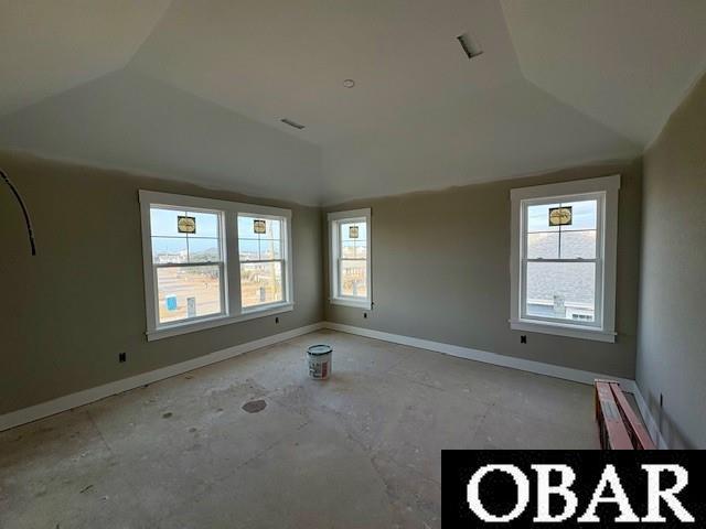 spare room featuring vaulted ceiling and baseboards