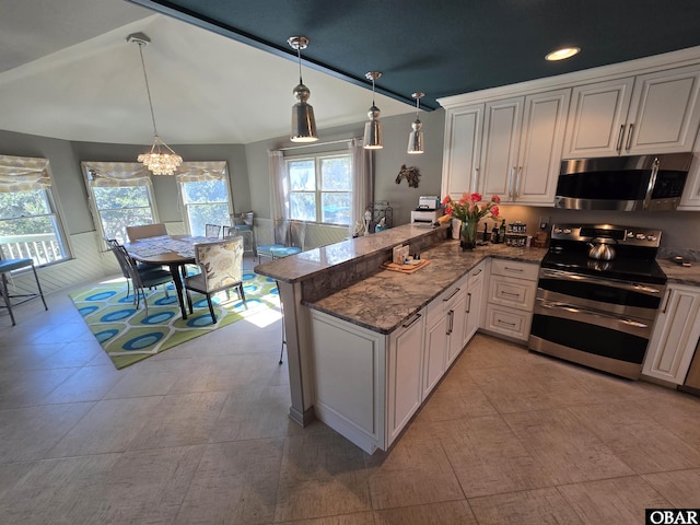 kitchen with stainless steel appliances, a peninsula, vaulted ceiling, hanging light fixtures, and dark stone counters