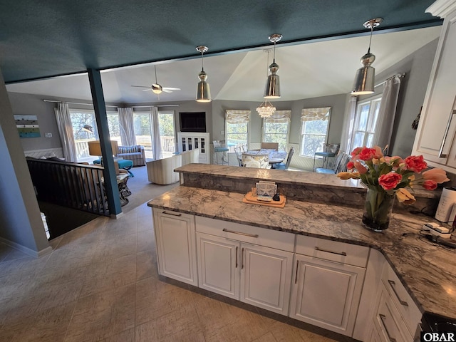 kitchen with a peninsula, a wealth of natural light, white cabinetry, and light stone countertops