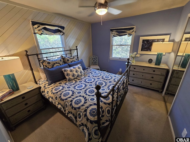 bedroom with carpet flooring, ceiling fan, and wooden walls