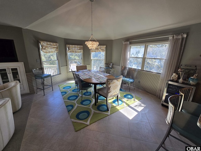 tiled dining area featuring vaulted ceiling, a wealth of natural light, and an inviting chandelier