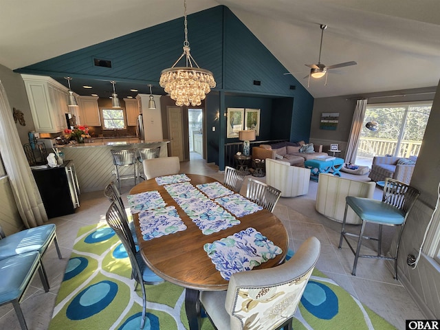 dining room with light tile patterned floors, high vaulted ceiling, and ceiling fan with notable chandelier