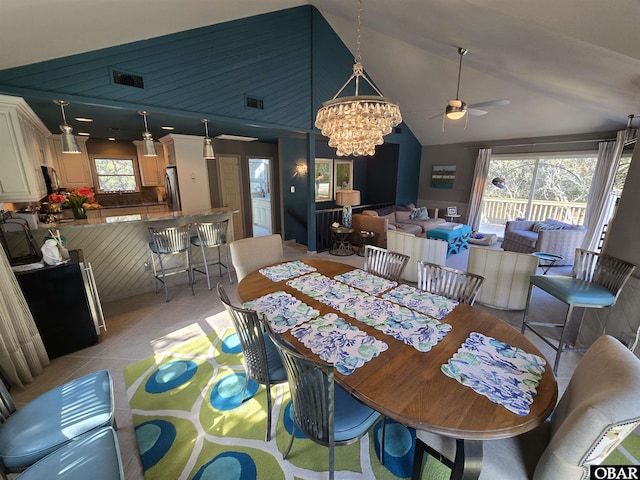 dining area with ceiling fan with notable chandelier, visible vents, vaulted ceiling, and light tile patterned floors