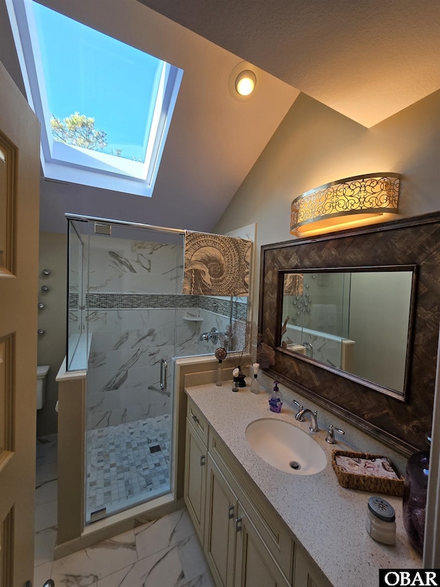 full bath featuring vaulted ceiling with skylight, toilet, marble finish floor, vanity, and a shower stall