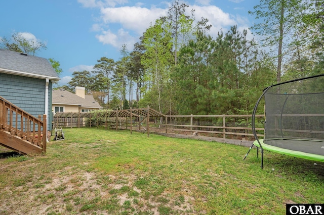view of yard featuring a trampoline and a fenced backyard