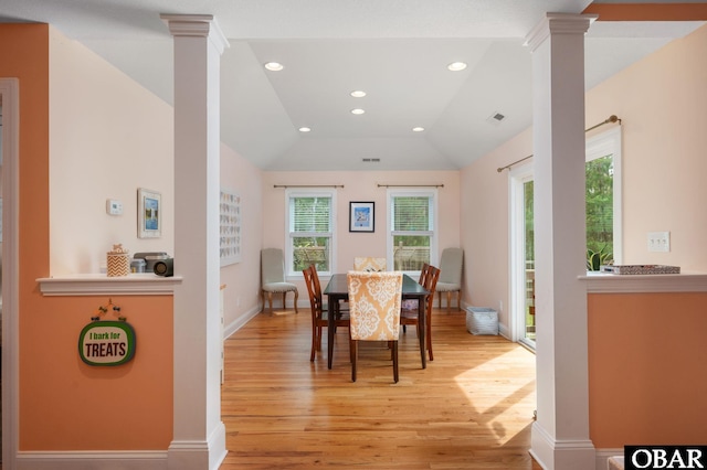 dining area featuring light wood-style floors, visible vents, ornate columns, and vaulted ceiling