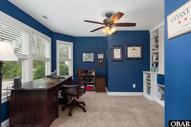 home office with visible vents, ceiling fan, light carpet, and baseboards