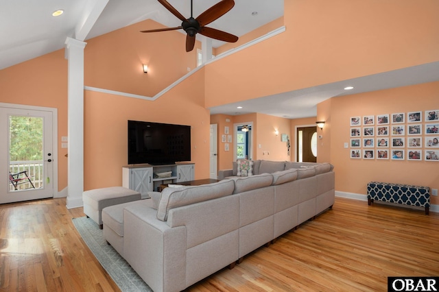 living area with light wood-type flooring, high vaulted ceiling, baseboards, and a ceiling fan