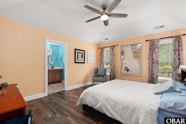 bedroom featuring baseboards, ensuite bath, visible vents, a raised ceiling, and wood finished floors