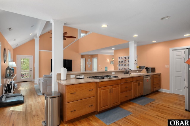 kitchen with open floor plan, appliances with stainless steel finishes, decorative columns, and light wood-style flooring