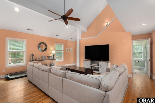 living room featuring visible vents, light wood-style flooring, a ceiling fan, and plenty of natural light