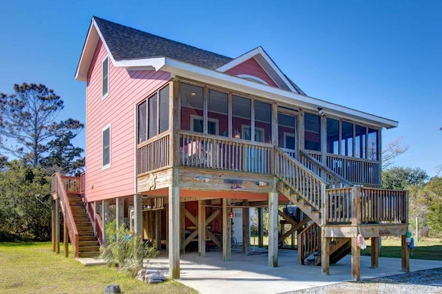 view of front of property featuring a carport, a sunroom, roof with shingles, and stairway