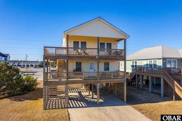 coastal inspired home with concrete driveway, a porch, stairway, and a balcony