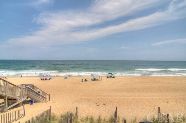 property view of water with a view of the beach and fence