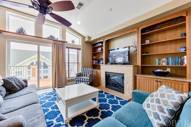 living room with built in features, a fireplace, visible vents, a ceiling fan, and vaulted ceiling