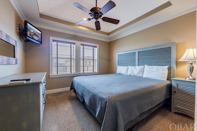 carpeted bedroom with baseboards, ceiling fan, a tray ceiling, and crown molding