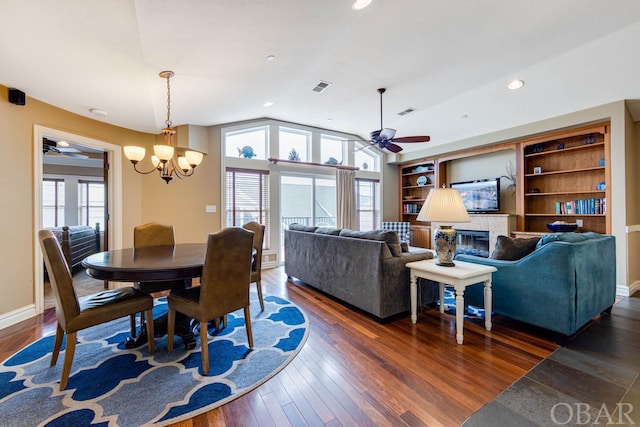 dining room featuring dark wood-type flooring, a glass covered fireplace, vaulted ceiling, and plenty of natural light