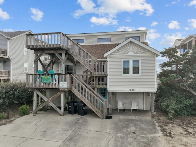 view of front of house featuring a deck, concrete driveway, stairway, and an attached garage