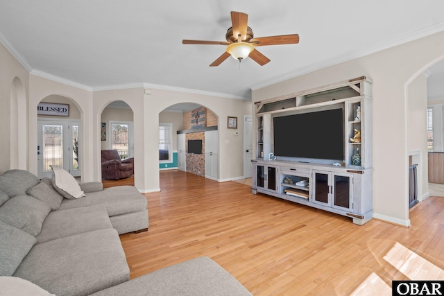 living room with ornamental molding, a healthy amount of sunlight, baseboards, and wood finished floors