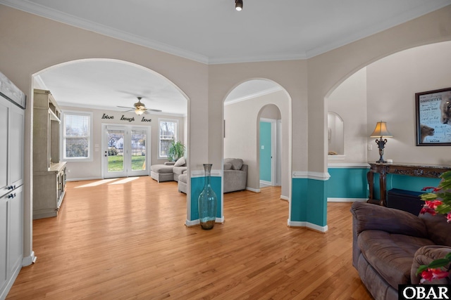 living area featuring light wood-type flooring, baseboards, and crown molding