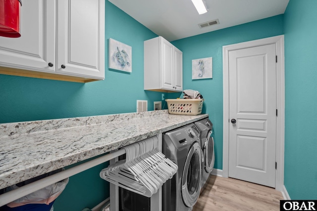 laundry room with cabinet space, baseboards, visible vents, washing machine and clothes dryer, and light wood-type flooring