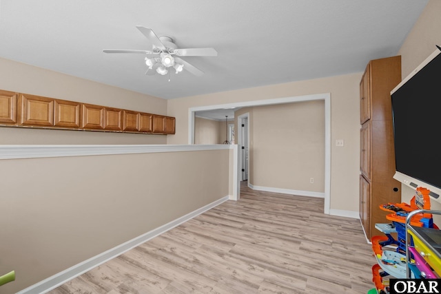 interior space featuring baseboards, ceiling fan, and light wood finished floors