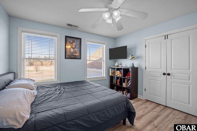 bedroom with ceiling fan, light wood finished floors, a closet, and visible vents