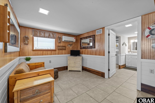 402 N Memorial Blvd Lot 3, Kill Devil Hills, NC 27948 - living area featuring an AC wall unit, wooden walls, light tile patterned floors, baseboards, and a wainscoted wall