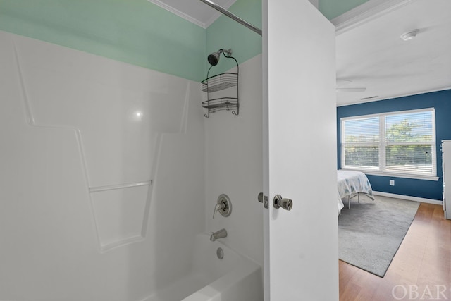 full bath featuring baseboards, connected bathroom, wood finished floors, crown molding, and shower / washtub combination