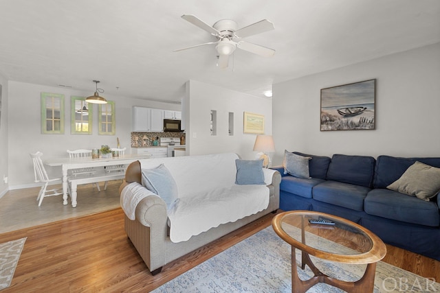 living area featuring baseboards, a ceiling fan, and light wood-style floors