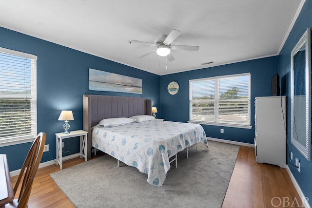 bedroom with ceiling fan, wood finished floors, visible vents, and baseboards