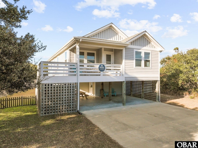 view of front of property with board and batten siding, concrete driveway, and a carport