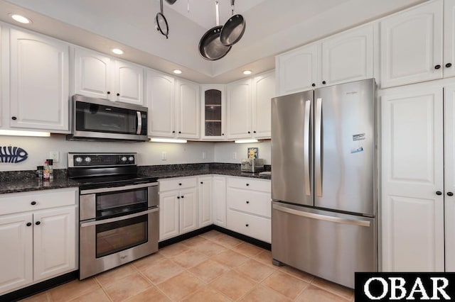 kitchen with dark stone counters, recessed lighting, white cabinets, glass insert cabinets, and appliances with stainless steel finishes