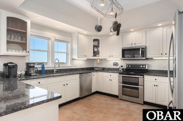 kitchen featuring white cabinetry, dark stone countertops, appliances with stainless steel finishes, and a sink