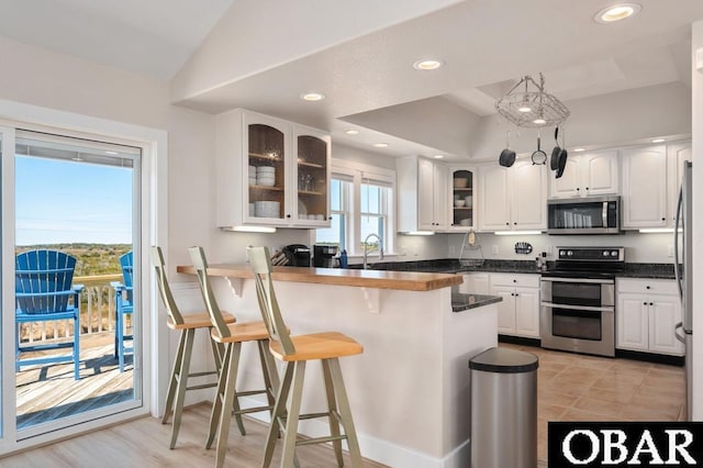 kitchen featuring a peninsula, appliances with stainless steel finishes, a breakfast bar area, and white cabinetry