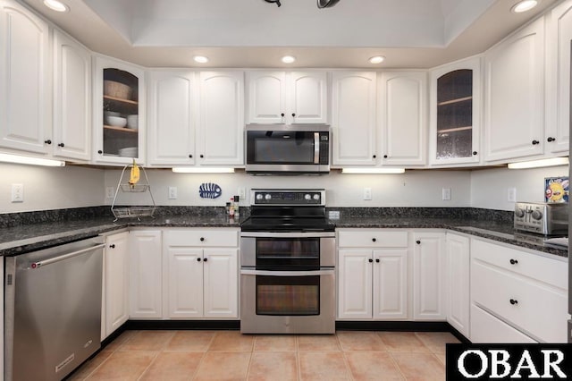 kitchen with recessed lighting, white cabinets, appliances with stainless steel finishes, and glass insert cabinets