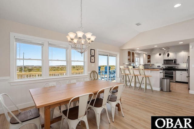 dining space with recessed lighting, an inviting chandelier, wainscoting, light wood finished floors, and vaulted ceiling