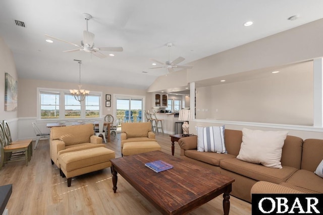 living room featuring light wood-type flooring, visible vents, ceiling fan with notable chandelier, recessed lighting, and vaulted ceiling