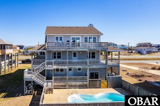 rear view of house featuring an outdoor pool, a patio, a balcony, and fence